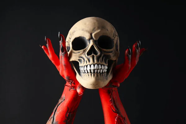 Creepy, red hands of the monster hold the skull