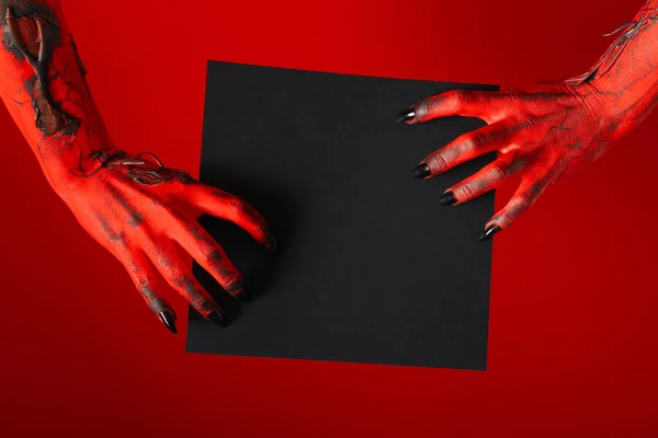 Spooky, red hands of the monster hold a black sheet