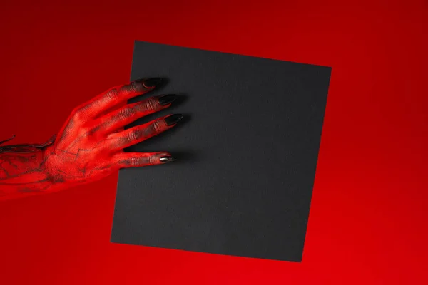Spooky, red hands of the monster hold a black sheet