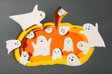 Gri arka planda kağıt balkabağı ve hayaletler, üst görünüm