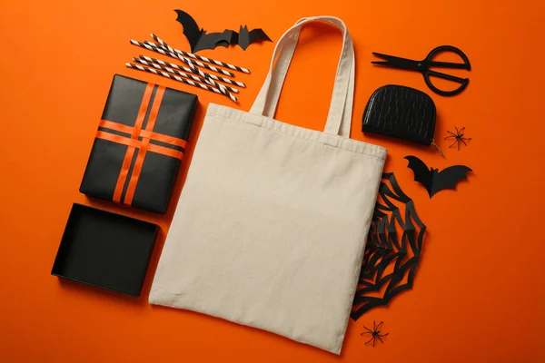 Gift box, cotton bag and scissors on orange background, top view