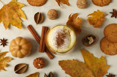 Beyaz arka planda balkabağı kahvesi, yapraklar ve tarçın, üst manzara.