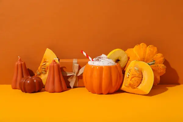 Coffee and pumpkins on orange background, space for text