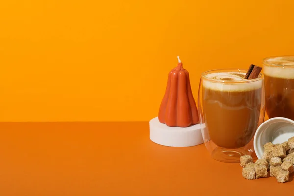 Pumpkin coffee and candle on orange background, space for text