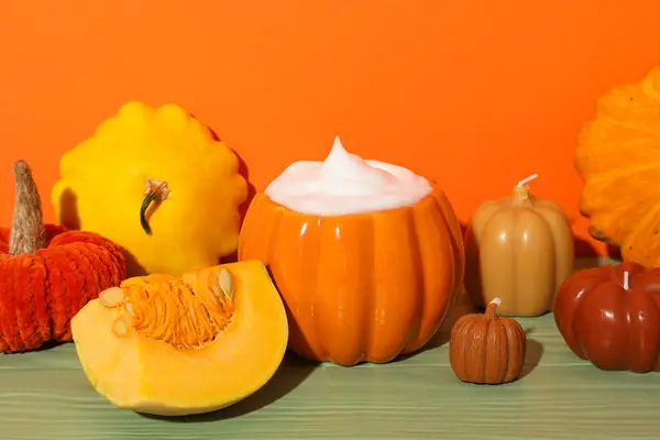 Coffee, pumpkins and candles on orange background