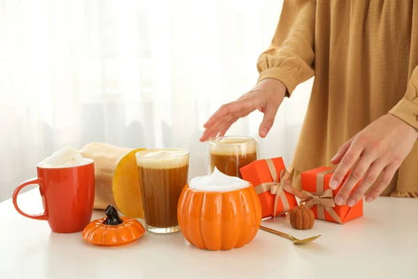 Pumpkin coffee, gift boxes, pumpkin and female hands on light background