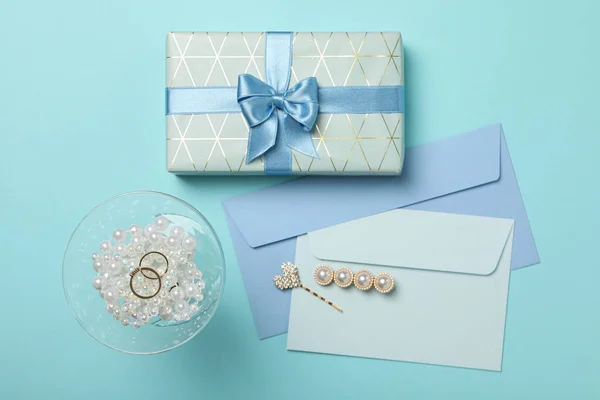Gift box, envelopes and wedding rings on blue background, top view