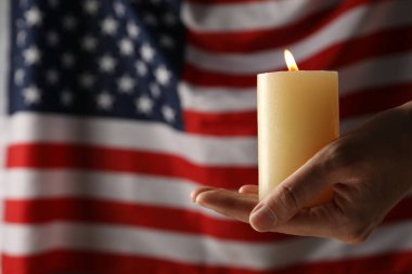 Amerikan bayrağının arka planında ellerinde yas tutan mum.