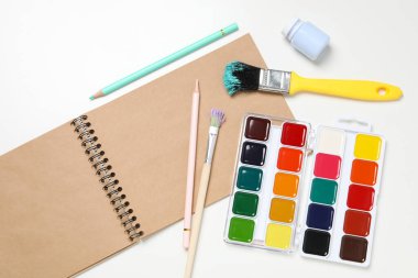 Albüm, fırçalar ve boyalar beyaz arkaplanda, üst görünümde