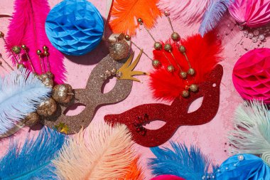 Pembe arka planda karnaval maskeleri ve tüyleri, üst manzara