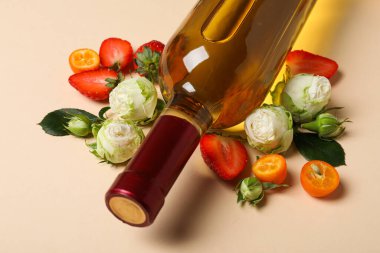 Şarap şişesi, güller ve bej arka planda meyveler, kapatın.