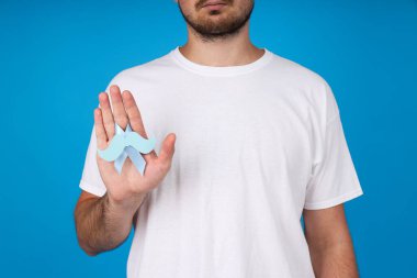 Bir adamın elinde bıyıklı mavi kurdele.