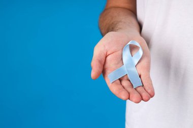 Bir adamın elinde mavi kurdele, Movember konsepti.