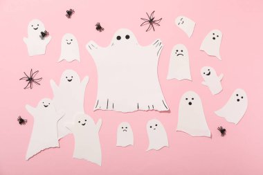 Kağıt hayaletler ve pembe arka planda dekoratif örümcekler.