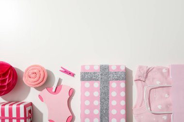 Beyaz arka planda hediye kutuları ve pembe bebek kıyafetleri, metin için boşluk