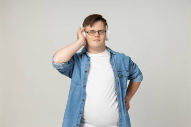 Gözlüklü, kot pantolonlu ve kameraya poz veren, beyin felçli gülümseyen genç bir adam. Dünya Genetik Hastalıklar Günü konsepti