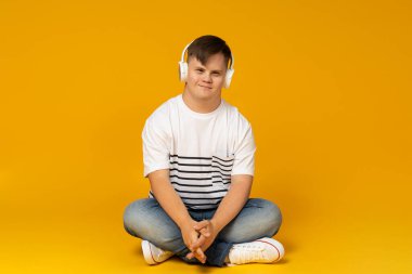 Gözlüklü, beyin felçli gülümseyen genç bir adam kulaklıkla müzik dinliyor. Dünya Genetik Hastalıklar Günü konsepti