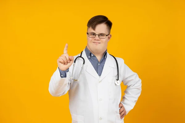stock image Smiling young man with cerebral palsy wearing glasses in doctor uniform with stethoscope. World Genetic Diseases Day concept