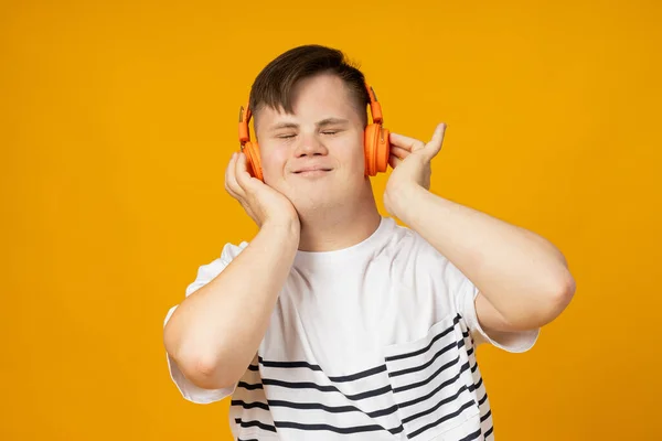 stock image A smiling young man with cerebral palsy in glasses listens to music in headphones. World Genetic Diseases Day concept