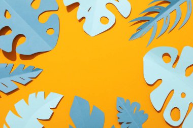 Sarı arka planda kağıt mavisi tropikal yapraklar.