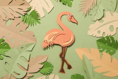 Yeşil arka planda kağıt yeşili tropikal yapraklar. Bir flamingo kuşuyla.