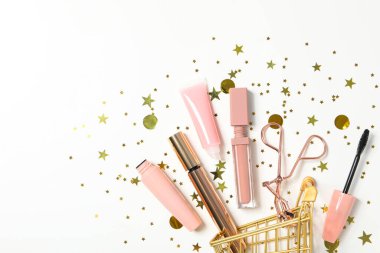 Pembe makyaj aksesuarlarıyla altın alışveriş sepeti