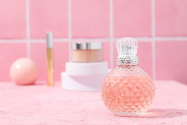Pembe arka planda makyaj aksesuarları olan parfüm