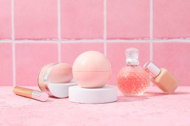 Pembe arka planda makyaj aksesuarları olan parfüm