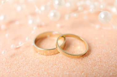 Bej arka planda altın alyanslar, yakın plan.