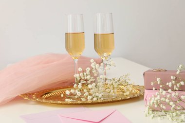 Arkaplanda şarap bulunan hediye kutuları, çiçekler ve bardaklar