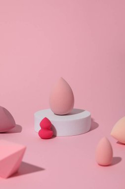 Pembe arka planda kozmetik süngerler ve beyaz blok