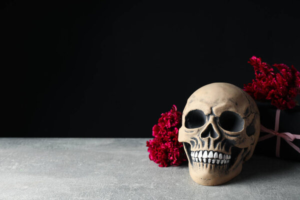 Skull and flowers on black background, space for text