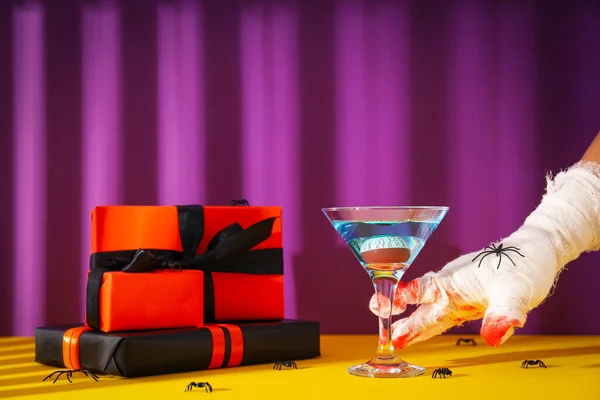 Hands wrapped in a bandage with a cocktail and gifts