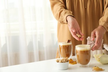Balkabağı kahvesi, yapraklar, hediye kutusu ve arka planda kadın eli, mesaj için yer