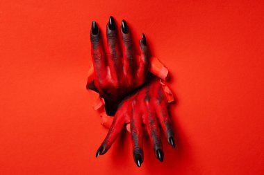 Kırmızı arka planda siyah tırnaklı kırmızı kadın elleri