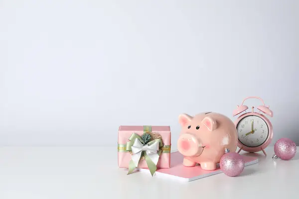 Piggy bank, gift box and alarm clock on white background, space for text