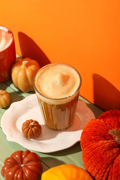 Pumpkin coffee and decorative pumpkins on orange background
