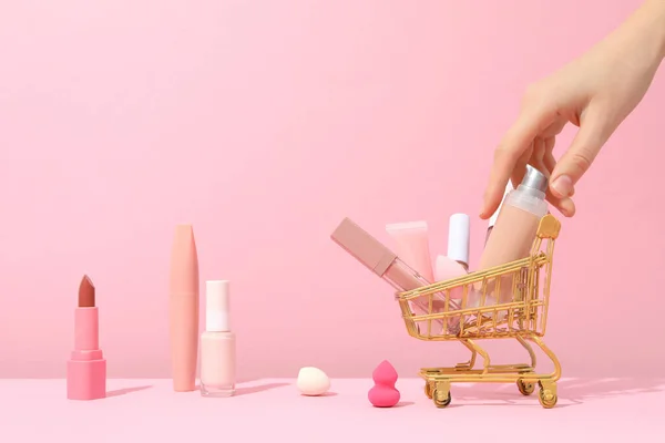 Golden shopping basket with pink makeup accessories