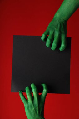 Yeşil, boyalı eller metin için bir mektup tutar.