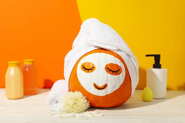 Skin and face care concept - pumpkin with face mask