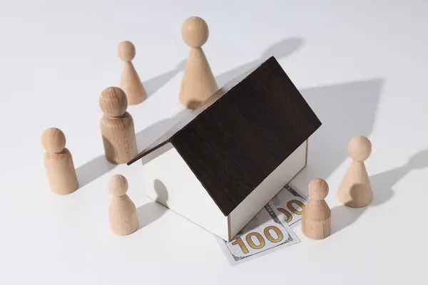 Wooden house, cash and wooden figures on white background