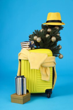 Süslü Noel ağacı ve şapkası olan sarı bir bavul.