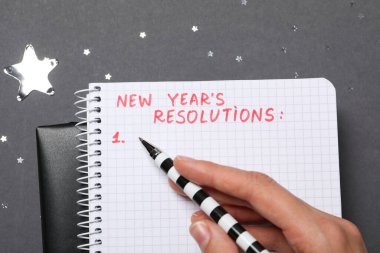 Elinde kalem ve gri arkaplanda metin olan not defteri, kapat