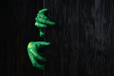 Green female hand on dark wooden background, space for text clipart