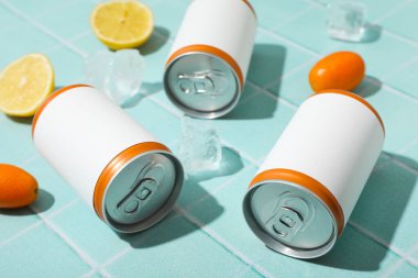 Mavi arka planda teneke kutular, buz küpleri ve narenciye meyveleri, kapatın.