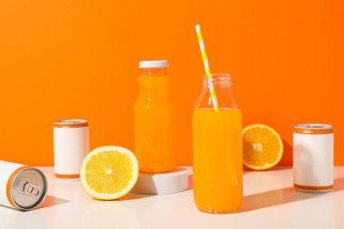 Turuncu arka planda teneke kutular, cam şişeler ve portakallar