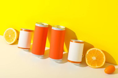 Sarı arka planda teneke kutular ve narenciye meyveleri