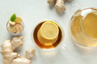 Çay fincanı ve çaydanlık, beyaz arka planda zencefil, üst manzara.