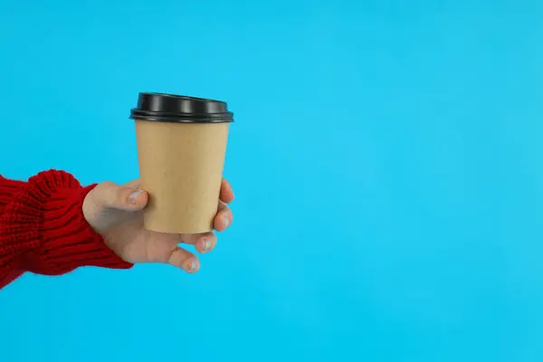 Coffee in a paper cup in hands. on a blue background.