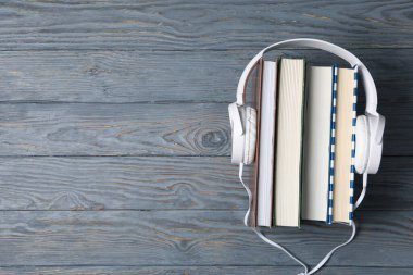 Ahşap arka plandaki kitaplardaki kulaklıklar, metin için boşluk